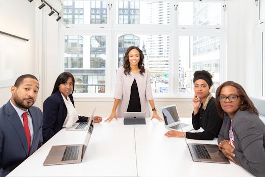 Home Professional team collaborating in a bright, modern conference room with laptops.